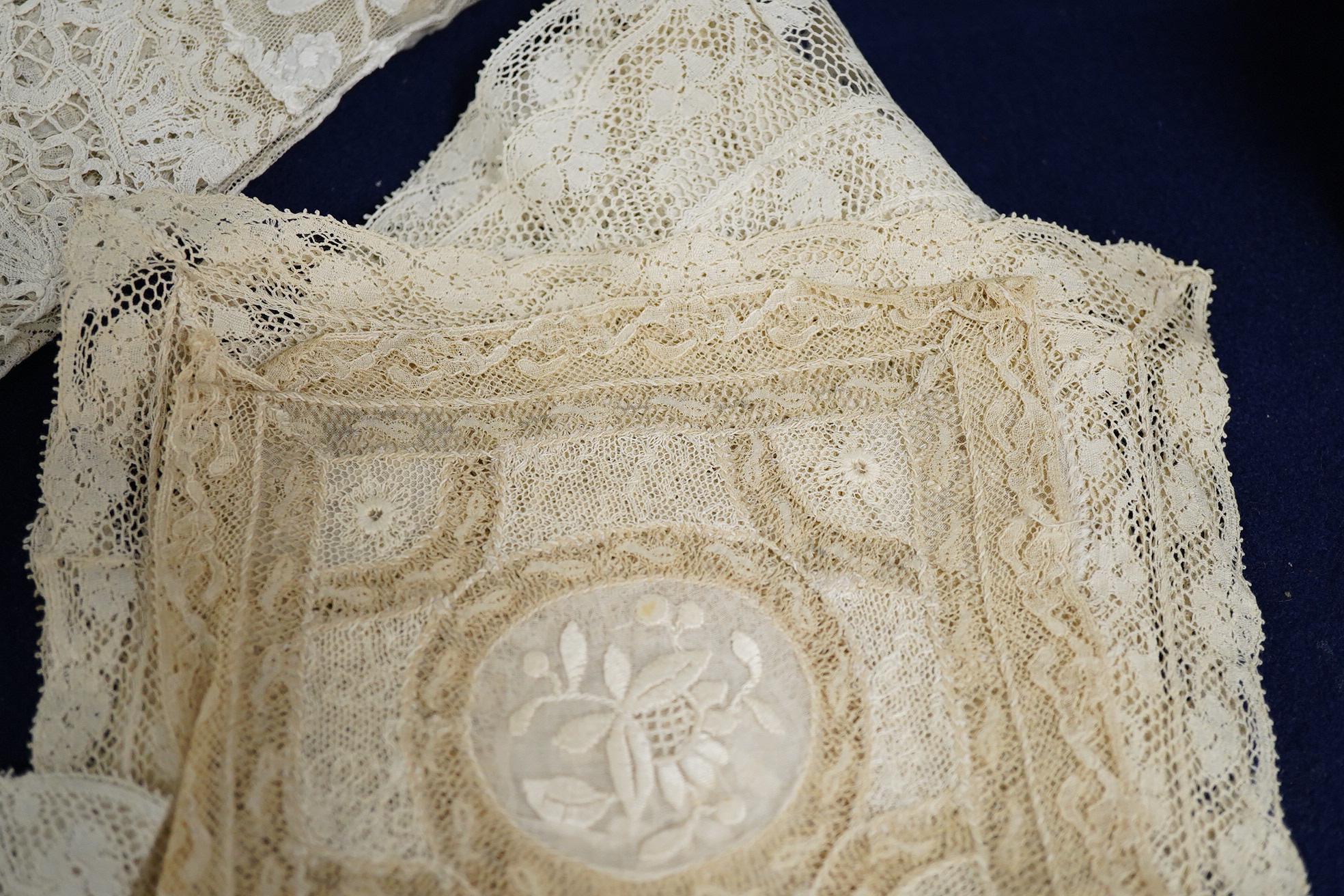 A late 19th / early 20th century circular Normandy lace table cover, with five similar smaller lace mats: all patch worked together from hand bobbin and hand needle laces, possibly part of a wedding trousseau. larger clo